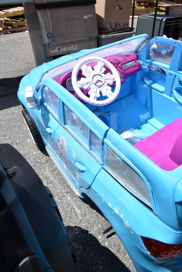Blue children's ride-on car, Mercedes model, Frozen II theme, features Elsa graphics, snowflake designs, pink interior.
