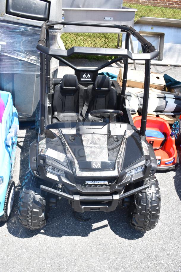 Ride On Children's Golf Cart, black with camo accents, features large wheels, two seats, "REALTREE" logo on front.