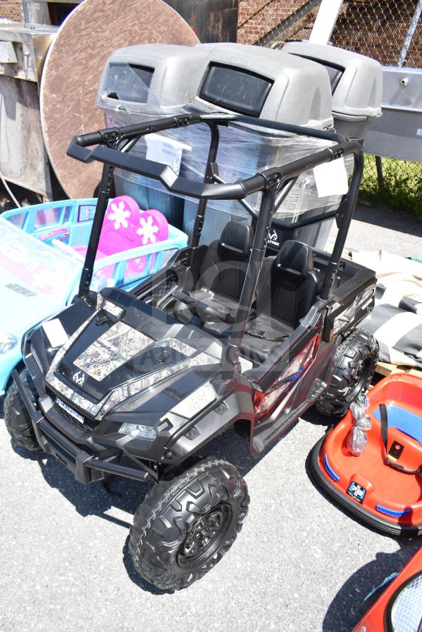 Children's ride-on golf cart, black with camo accents, two seats, rugged tires, in new condition.