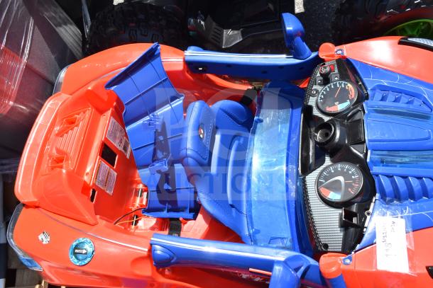 Red and blue ride-on Spiderman car for children featuring detailed dashboard and stickers, shown in fair condition.