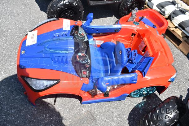 Red and blue Spiderman ride-on car for children, featuring decorative dashboard and graphics. Appears in good condition.