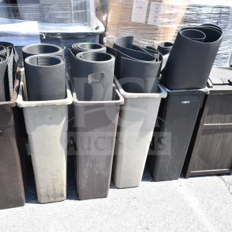 Six Slim Jim trash cans with rolled mats inside, various colors, outdoor setting, some wear visible, displayed for auction.