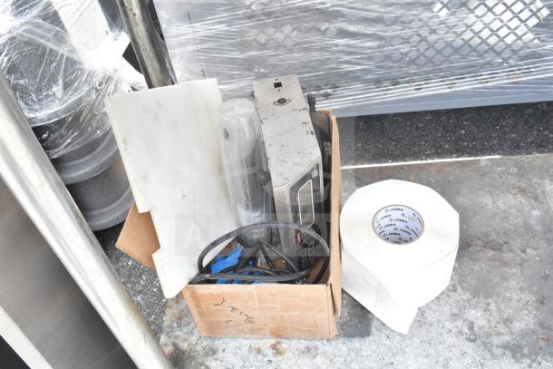 Cardboard box with various packing supplies, including wrapped plastic sheets and a roll labeled "Zebra."