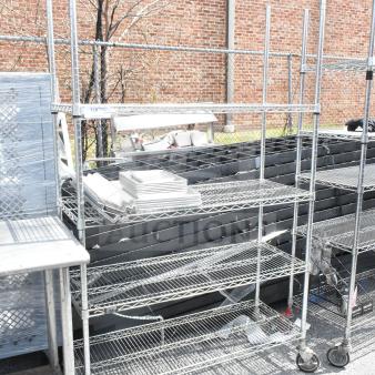 Chrome finish 4-tier wire shelving unit on commercial casters, dismantling required, visible in outdoor setting.