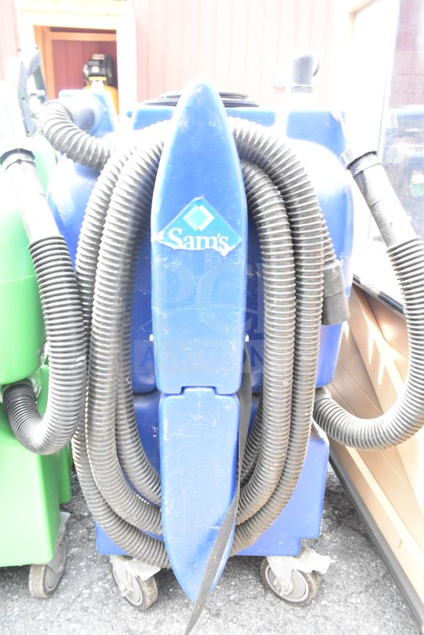 Two Sam's floor cleaning machines, blue, with hoses and wheels. Visible wear.