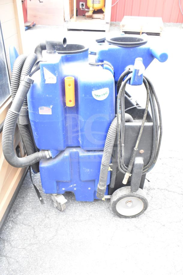 Two blue floor cleaning machines with hoses and wheels. Visible stickers and worn condition. Auction item, 2 for 1 bid.