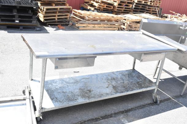 Commercial table with under shelf, two drawers, and casters. Metal construction, worn condition, ideal for industrial use.