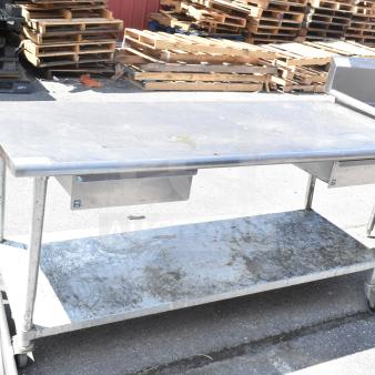 Commercial table with under shelf, two drawers, and casters. Metal construction, worn condition, ideal for industrial use.