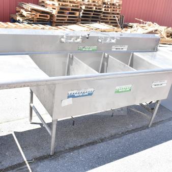 Commercial 3 bay stainless steel sink with dual drain boards, faucet handles, and visible water line labels, good condition.