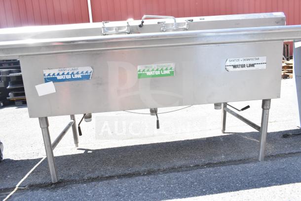 Commercial 3 bay sink with dual drain boards, stainless steel, visible water line labels for wash, rinse, and sanitize.