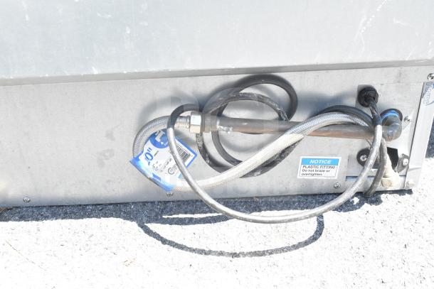Hoshizaki commercial self-contained ice machine, visible external connections, metal fittings, "Notice" label for instructions.