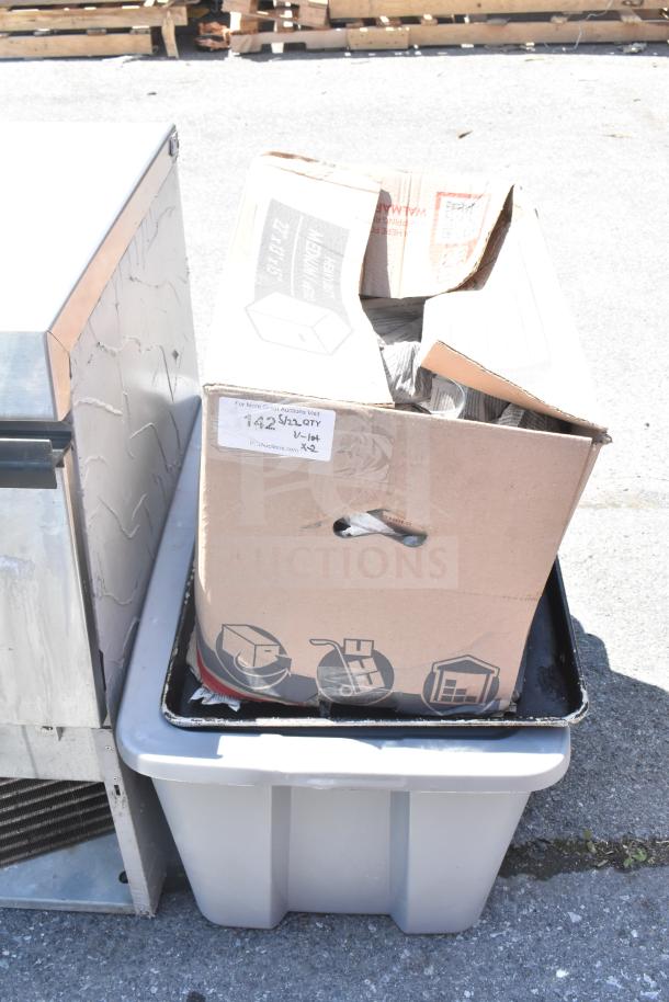 Cardboard box with glasses, mugs, and plates, placed on a plastic bin. Visible item tag marked "142" for auction.