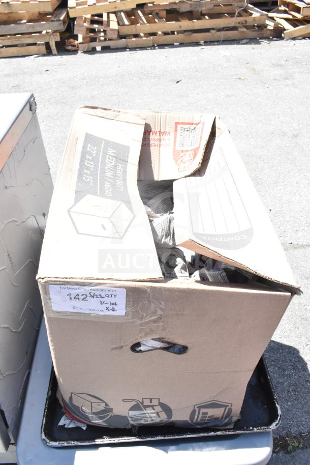 Two boxes containing assorted glasses, mugs, and plates. Boxes labeled "142" and "5/22 QTY x2." Auction item.