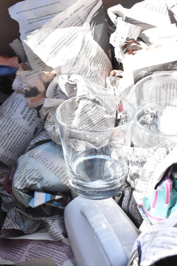 Two boxes containing assorted items such as glasses, mugs, and plates wrapped in newspaper, all in good condition.