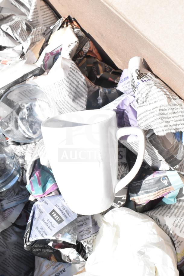 Two boxes of mixed kitchenware including a white mug, glass bowl, and wrapped items. Auction item, doubles your bid.