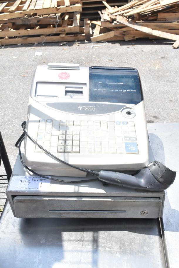 TE-2200 countertop electronic cash register with keypad and cash drawer. Includes attached barcode scanner. Visible wear.