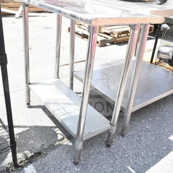 Chrome commercial table with under shelf, sturdy construction, showing signs of use. Ideal for kitchen or retail use.