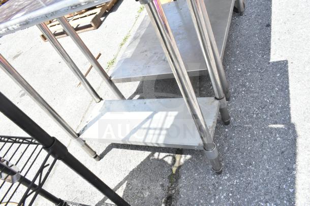 Commercial table with under shelf, stainless steel construction, sturdy legs, visible wear, suitable for kitchen or storage.
