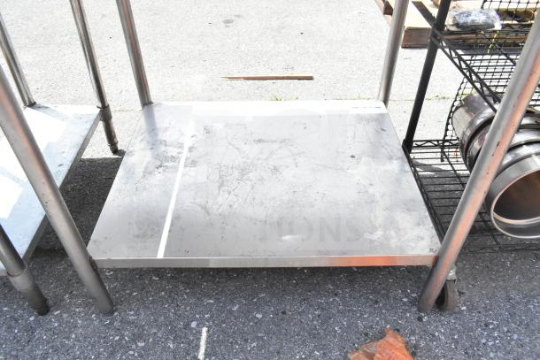 Commercial table with under shelf, stainless steel, used condition, visible scratches on surface, sturdy metal legs.