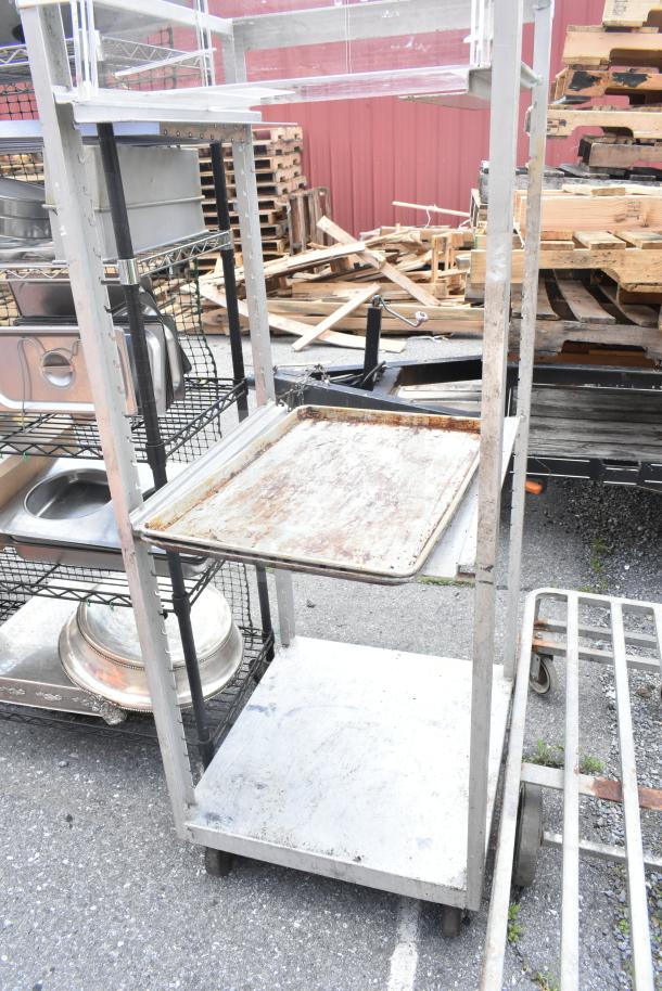 Commercial pan transport rack with sturdy metal frame on commercial casters, visible wear, ideal for kitchen use.