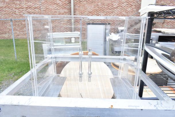 Commercial pan transport rack with clear panels, chrome handles, and metal frame on commercial casters. Rugged outdoor condition.