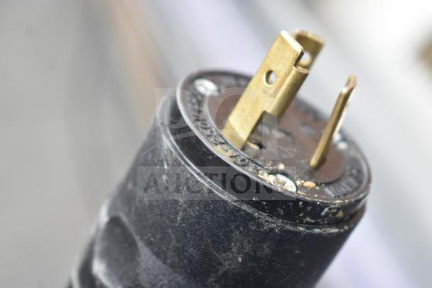 Close-up of power plug for a Commercial Floor Style Open Grab N Go Merchandiser, showing 120/208-240 volts, with moderate wear.