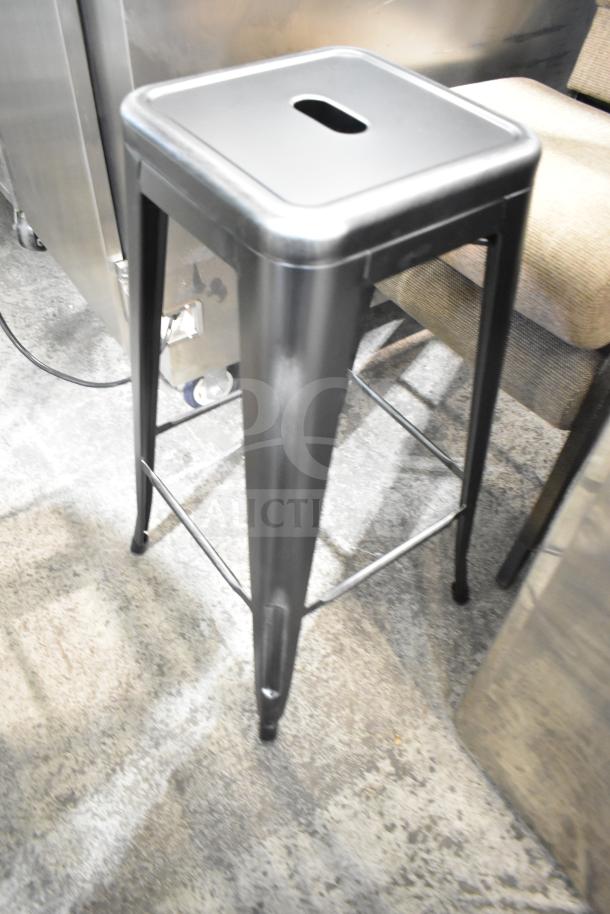 Metal bar stool with square seat and footrest, part of four-item set including two stools and two chairs.