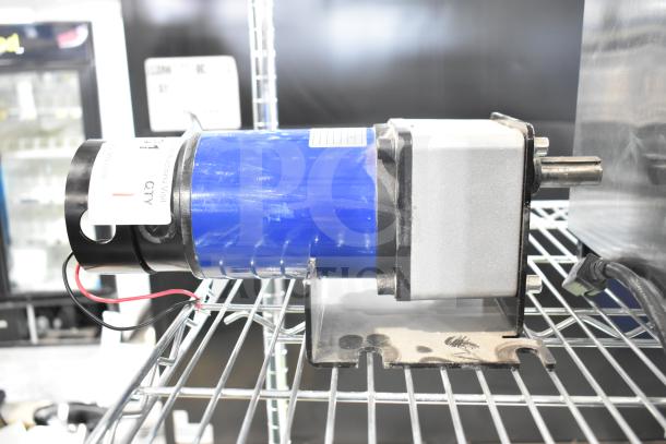 100ZYT51-GK60 motor, 130 volts, 1 phase, blue casing, wires attached, mounted on a shelf, label indicates specifications.