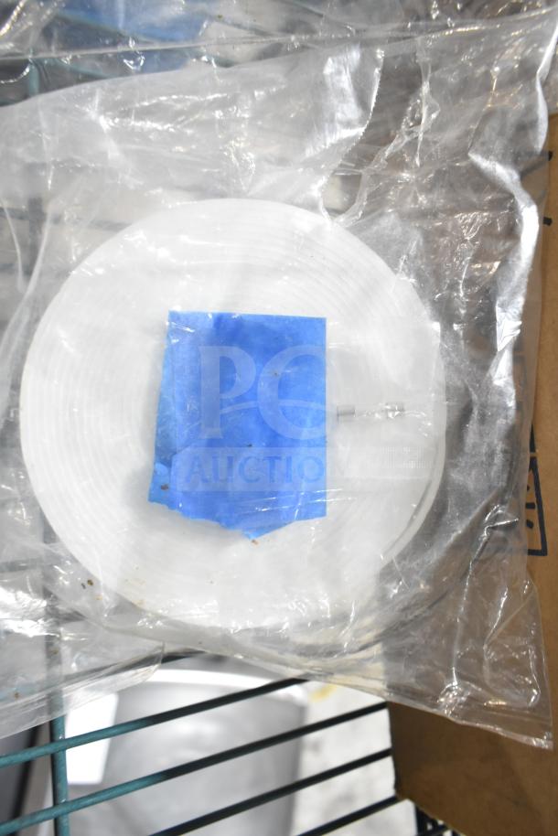 Plastic-wrapped white spool with blue tape, possibly wax ribbons. Condition appears new, part of auction set.