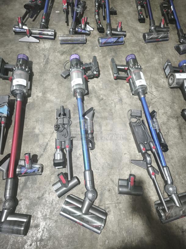 Dyson V11 Torque Drive PLUS cordless stick vacuum, tested and working, shown with attachments on concrete floor.