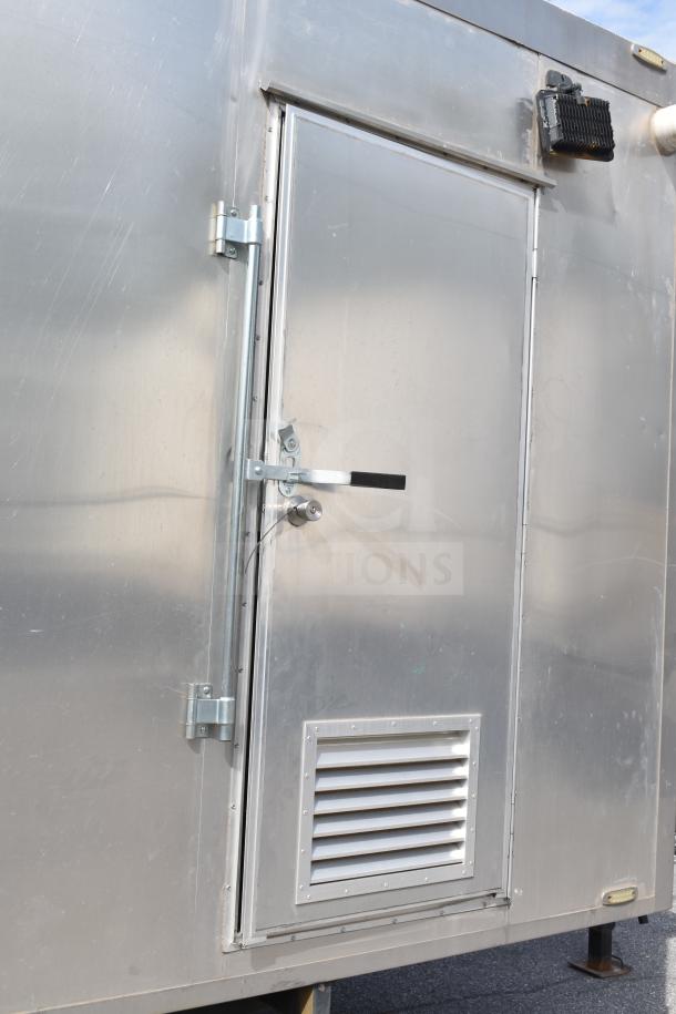 Exterior of a 2021 Texino 28ft triple-axle food trailer, featuring a metal door with vent and secure latch.