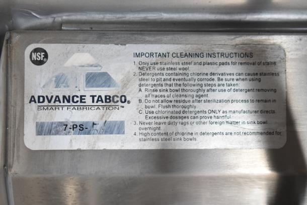 Alt text: "Advance Tabco label with cleaning instructions, NSF certification, and model number 7-PS-5 on stainless steel surface."