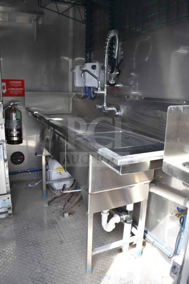 2021 Texino 28ft food trailer interior, featuring stainless steel sink and faucet, with visible plumbing and safety signage.