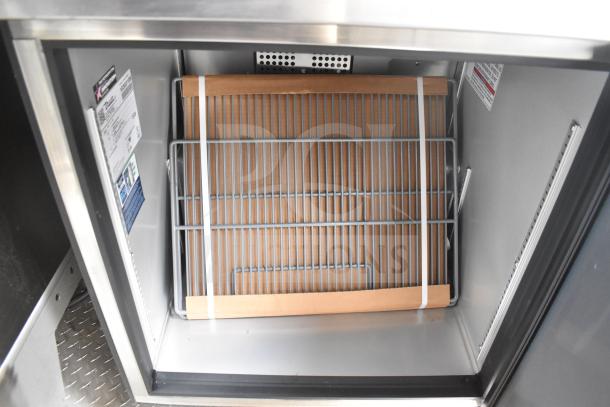Interior view of a Texino food trailer's True Refrigeration unit, showing a metal rack with tags indicating model details.
