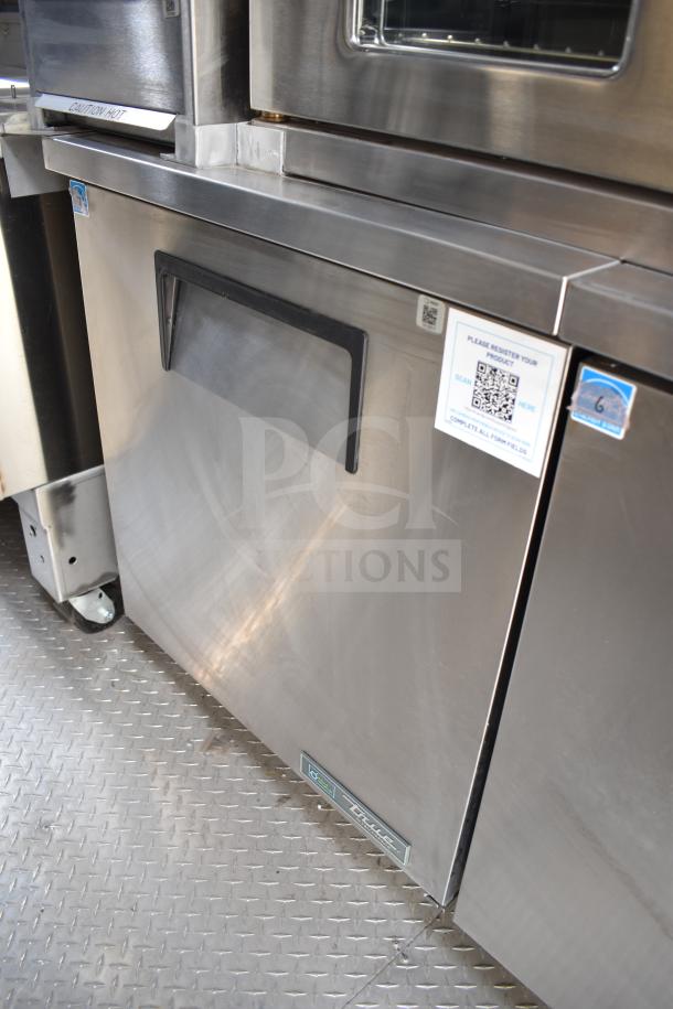 2021 Texino 28ft food trailer interior with True refrigeration unit and labeling for CaptiveAire system.