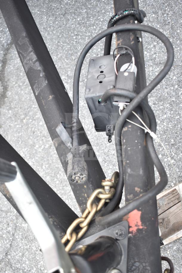 Close-up of hitch and wiring of 2021 Rock Solid Cargo 28ft food trailer. Features a sturdy chain and connections.