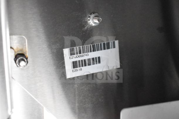 Barcode label on Texino 2021 food trailer component, reading "E21JD059743" and "E20-18," affixed to metal surface.