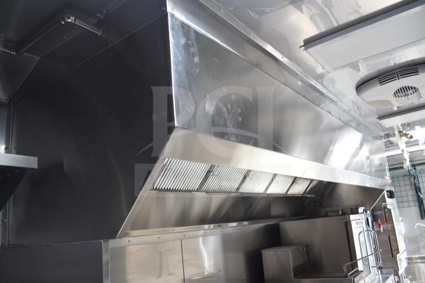 2021 Texino 28ft food trailer interior view, featuring CaptiveAire hood system and stainless steel kitchen setup.