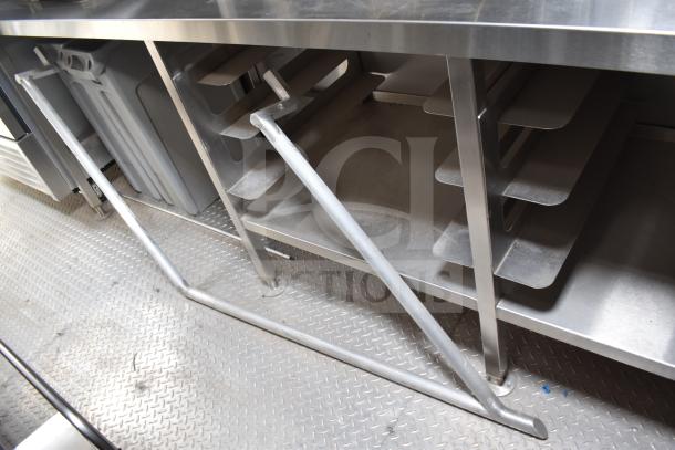 Interior view of a 2021 Texino 28ft food trailer, showcasing a stainless steel countertop with shelving and industrial flooring.