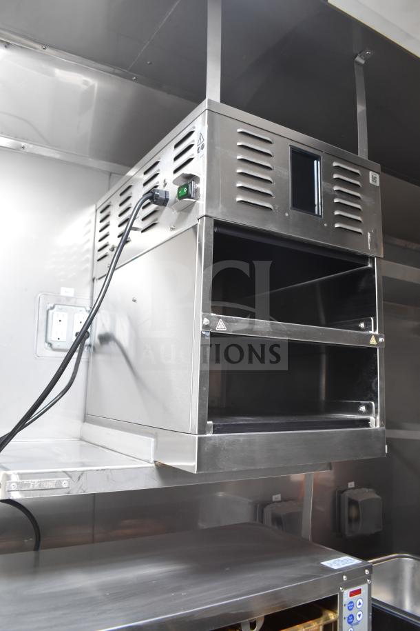 2021 Texino 28ft food trailer, inside view of stainless steel interior, CaptiveAire hood, visible electrical outlets.