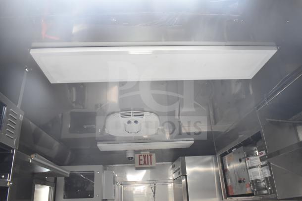 Interior view of a 2021 Texino 28ft food trailer, featuring a CaptiveAire hood and commercial kitchen equipment.