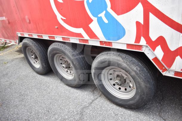 Triple-axle wheels of a 2021 Rock Solid Cargo 28ft food trailer with red and white graphics.