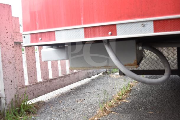 Underside of 2021 Rock Solid Cargo 28ft triple-axle food trailer showing utility connections and diamond plate design.