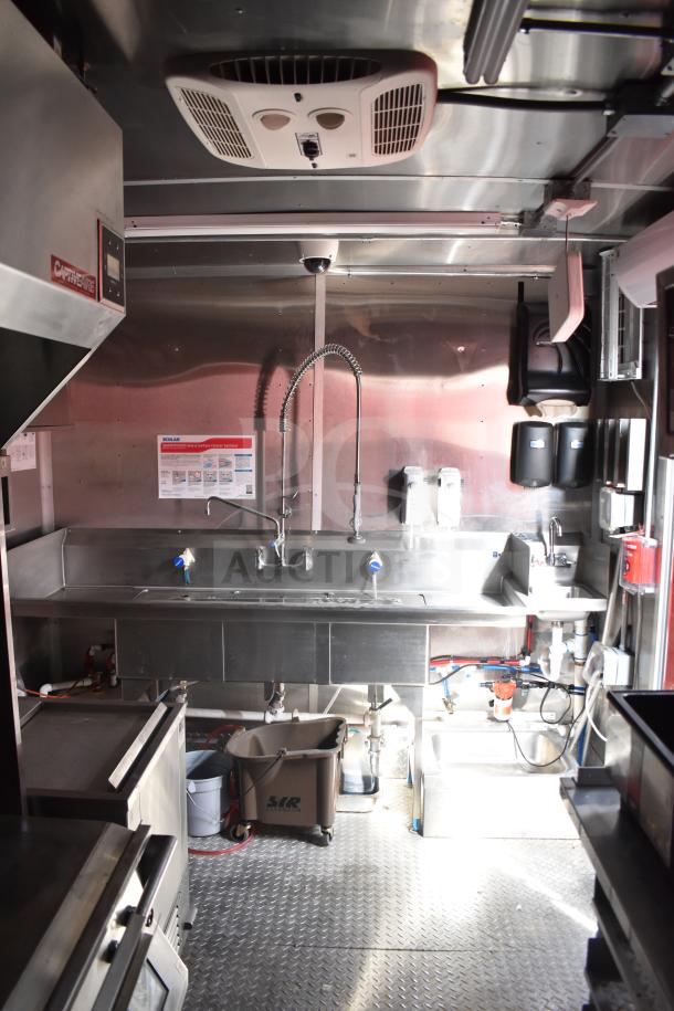 Interior of 2021 Rock Solid Cargo 28ft triple-axle food trailer with sink, CaptiveAire hood, and kitchen equipment.