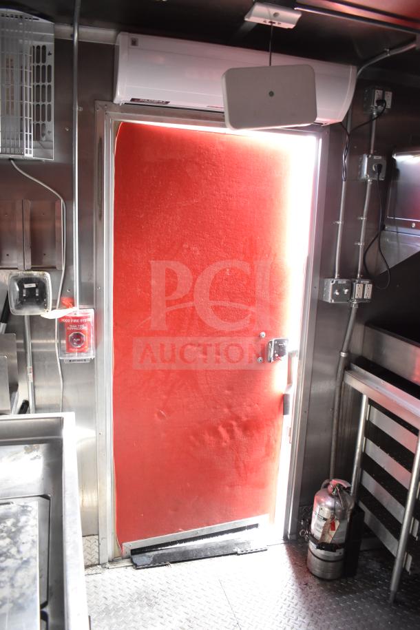 Interior of a 2021 Rock Solid Cargo 28ft food trailer with red door, climate control unit, and fire extinguisher in view.