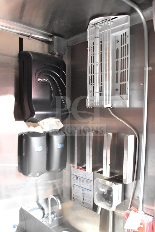 Inside view of 2021 Rock Solid Cargo food trailer, featuring a San Jamar paper towel dispenser, dual soap dispensers, sink, and storage racks.