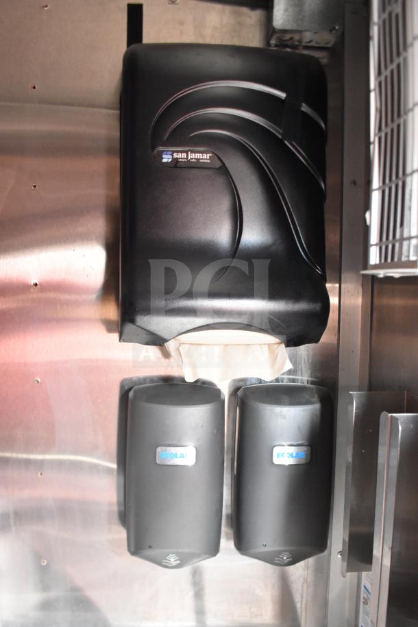 San Jamar paper towel dispenser with Ecolab soap dispensers mounted on a stainless steel surface inside the trailer.