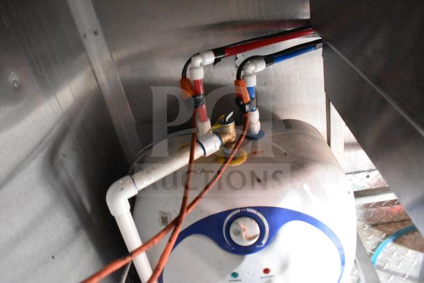Under-counter water heater with installed plumbing in a 2021 Rock Solid Cargo 28ft food trailer.
