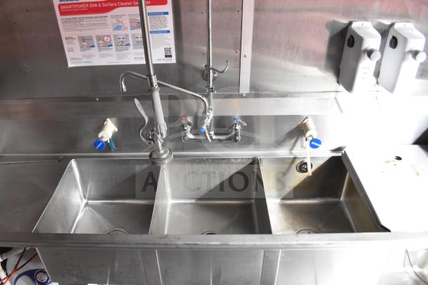 Triple-sink setup in a 2021 Rock Solid Cargo food trailer, featuring stainless steel construction and labeled sanitizer instructions.