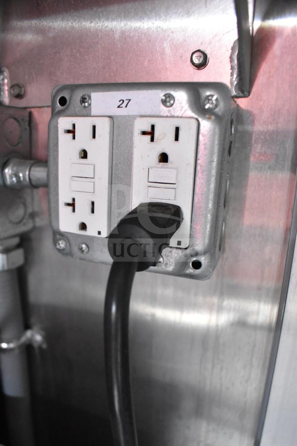 Dual electrical outlets in a Rock Solid Cargo trailer, labeled "27," with a plugged-in cord.